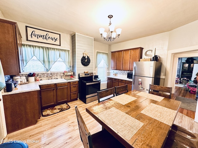 kitchen with stainless steel appliances, a notable chandelier, decorative backsplash, decorative light fixtures, and light wood-type flooring