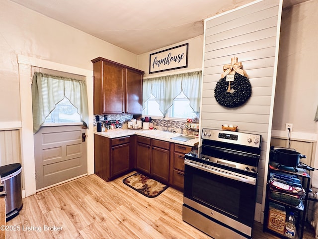 kitchen featuring light hardwood / wood-style floors, sink, stainless steel electric range, and backsplash