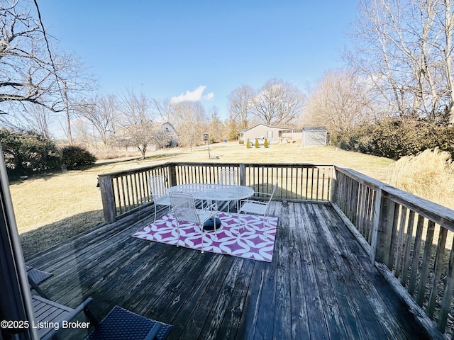 wooden terrace with a storage shed and a lawn