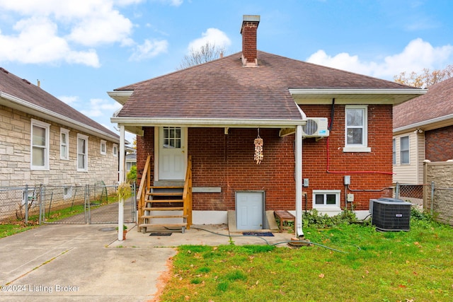 back of house with central AC unit and a lawn