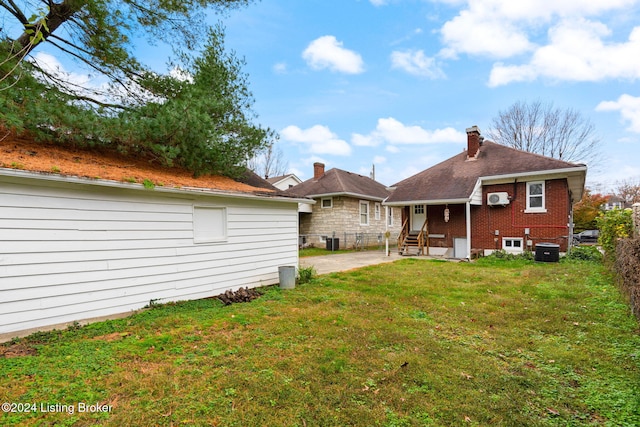 back of house with central AC unit and a yard