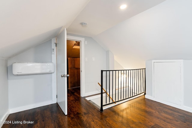 additional living space featuring dark wood-type flooring, vaulted ceiling, and a wall unit AC