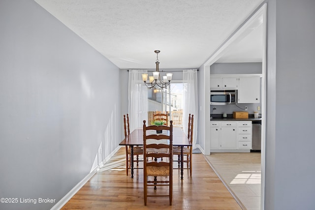 dining room featuring an inviting chandelier, a textured ceiling, and light wood-type flooring