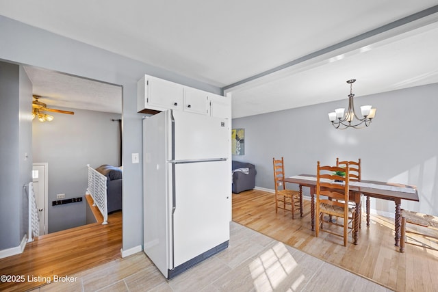 kitchen with decorative light fixtures, light hardwood / wood-style floors, white fridge, and white cabinets