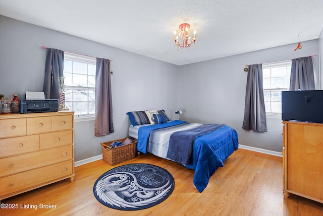 bedroom with an inviting chandelier, a textured ceiling, and light hardwood / wood-style floors