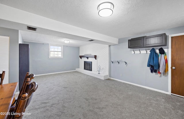 basement with carpet, a brick fireplace, and a textured ceiling