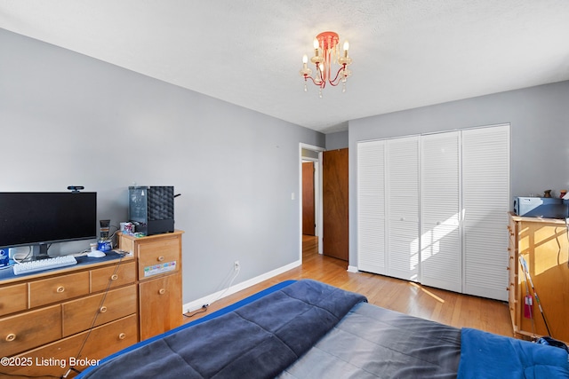 bedroom with an inviting chandelier, light hardwood / wood-style flooring, and a closet