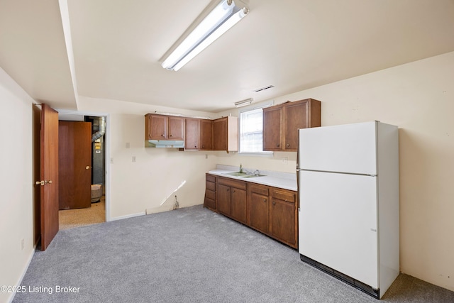 kitchen featuring white refrigerator, sink, and light carpet