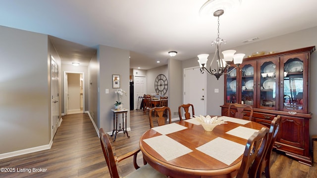 dining area featuring dark wood-type flooring and a notable chandelier