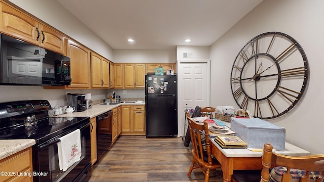 kitchen with light stone counters, black appliances, and dark hardwood / wood-style floors