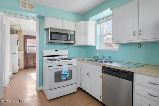 kitchen featuring white cabinetry, stacked washer and dryer, stainless steel appliances, and sink