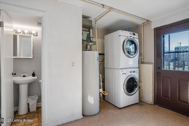 laundry room featuring sink, water heater, and stacked washing maching and dryer