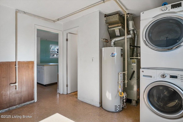 clothes washing area featuring gas water heater and stacked washer / drying machine