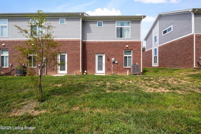 rear view of house featuring central AC unit and a lawn