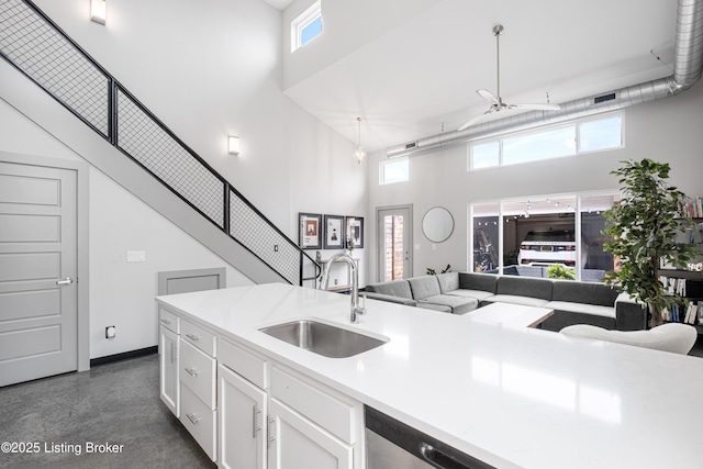 kitchen featuring a high ceiling, hanging light fixtures, sink, and white cabinets