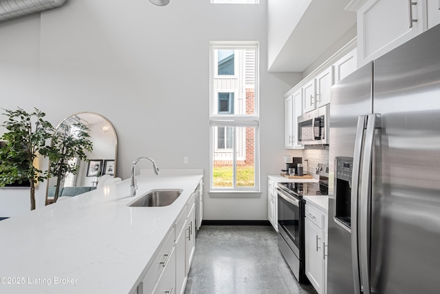 kitchen featuring sink, white cabinets, decorative backsplash, stainless steel appliances, and light stone countertops