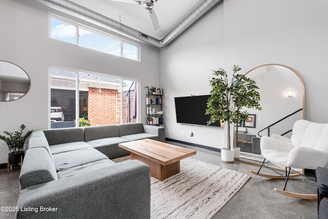 living room featuring concrete flooring, plenty of natural light, and a towering ceiling