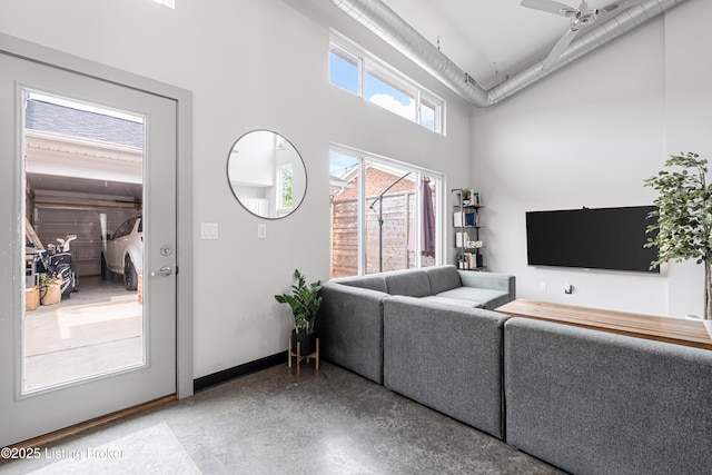 living room with ceiling fan and a towering ceiling