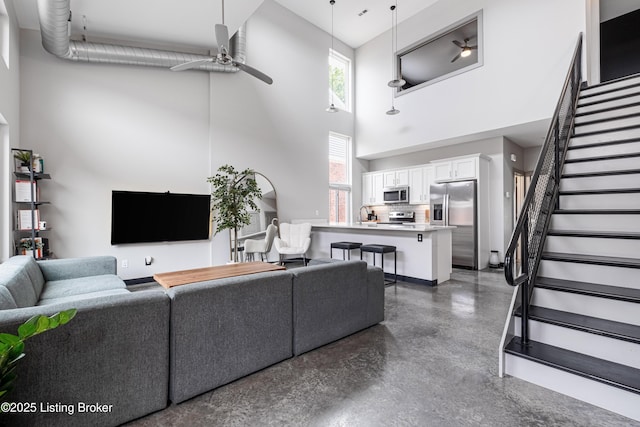 living room with sink, ceiling fan, and a high ceiling