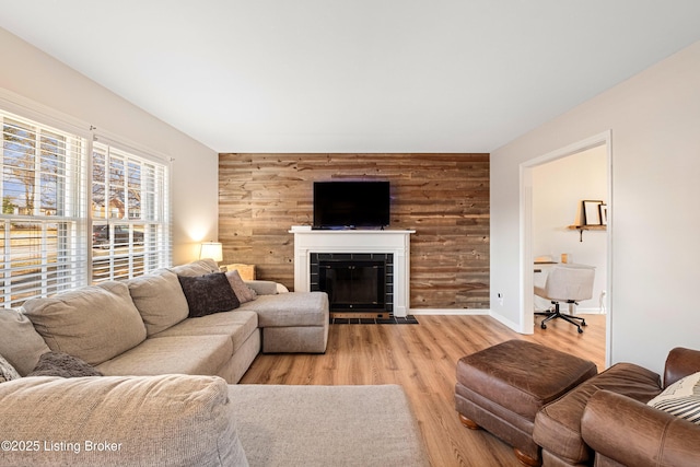 living room featuring a fireplace, wooden walls, and light hardwood / wood-style floors