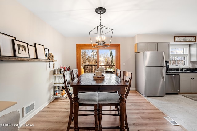 dining space with a chandelier, sink, and light wood-type flooring