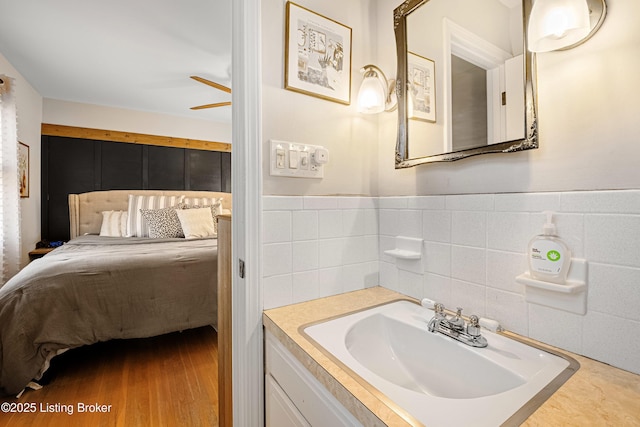 bathroom with hardwood / wood-style flooring, vanity, tile walls, and ceiling fan