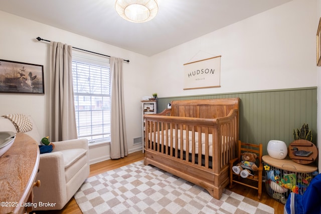 bedroom with a nursery area and light hardwood / wood-style floors