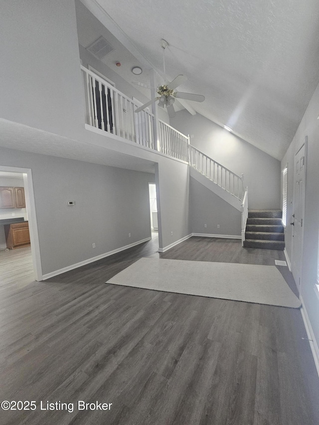 unfurnished living room featuring a textured ceiling, high vaulted ceiling, dark hardwood / wood-style floors, and ceiling fan