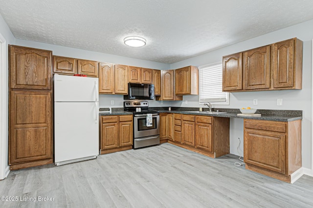 kitchen featuring white refrigerator, sink, stainless steel range with electric cooktop, and light hardwood / wood-style flooring