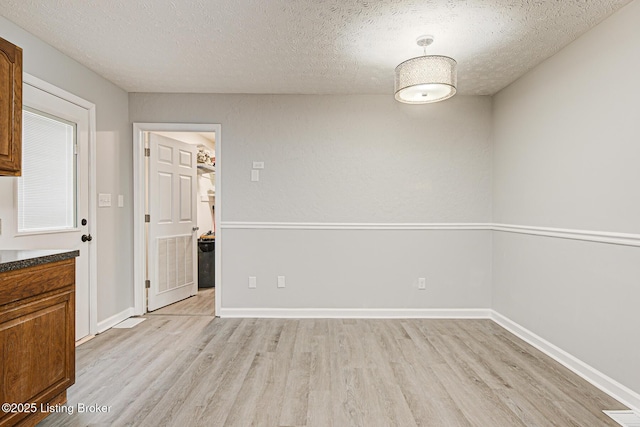 unfurnished dining area featuring light hardwood / wood-style floors and a textured ceiling