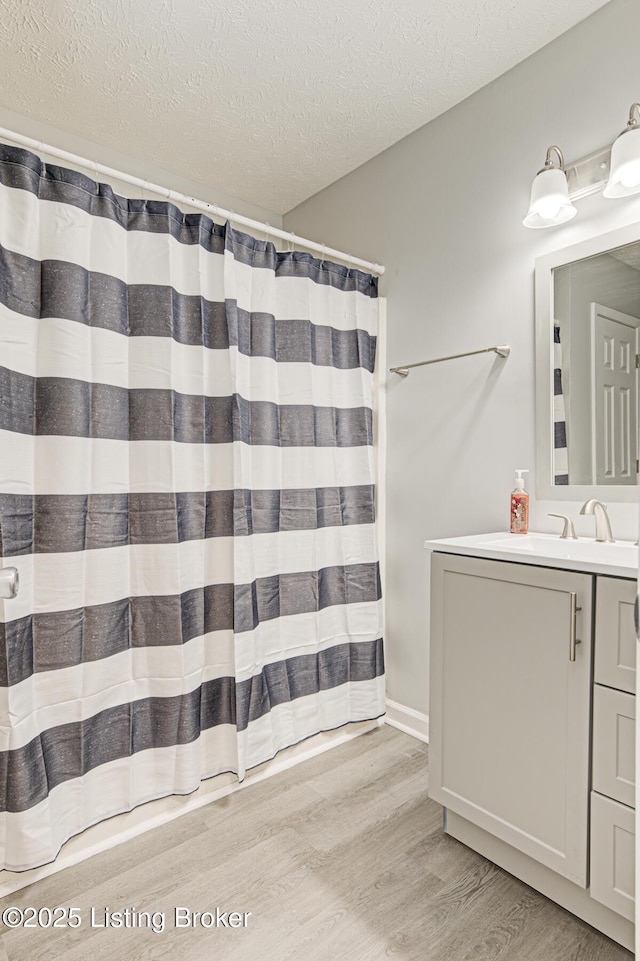 bathroom featuring hardwood / wood-style flooring, vanity, walk in shower, and a textured ceiling