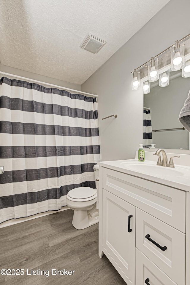 bathroom with vanity, hardwood / wood-style flooring, toilet, and a textured ceiling