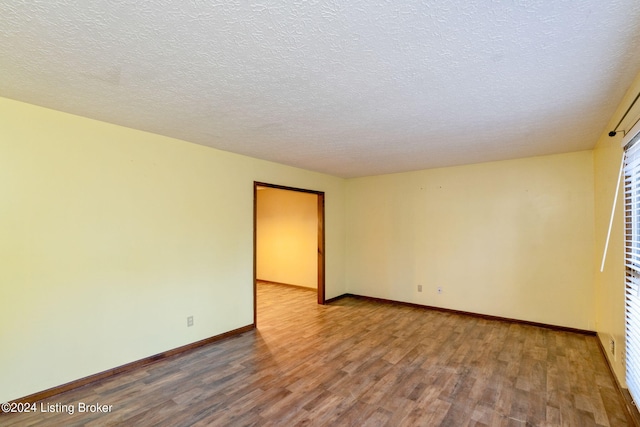 spare room featuring hardwood / wood-style flooring and a textured ceiling