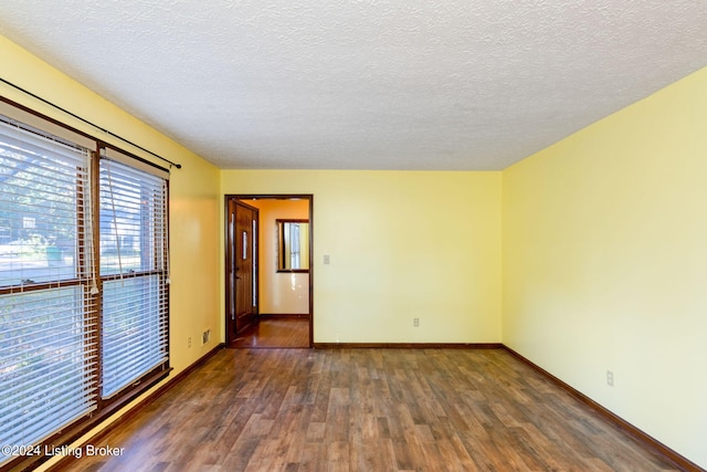 unfurnished room with dark hardwood / wood-style floors and a textured ceiling