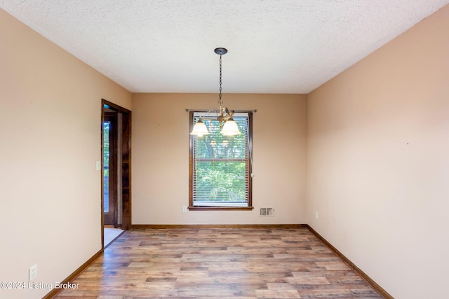 unfurnished dining area featuring light hardwood / wood-style floors and a textured ceiling