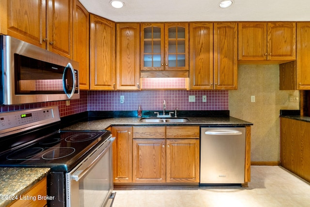 kitchen featuring backsplash, stainless steel appliances, sink, and dark stone countertops