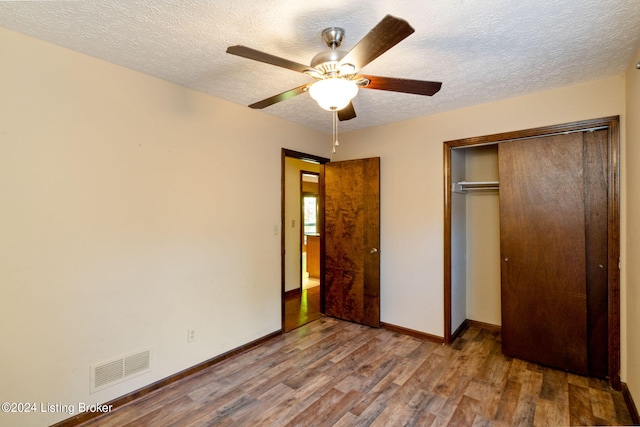 unfurnished bedroom featuring ceiling fan, hardwood / wood-style floors, a closet, and a textured ceiling