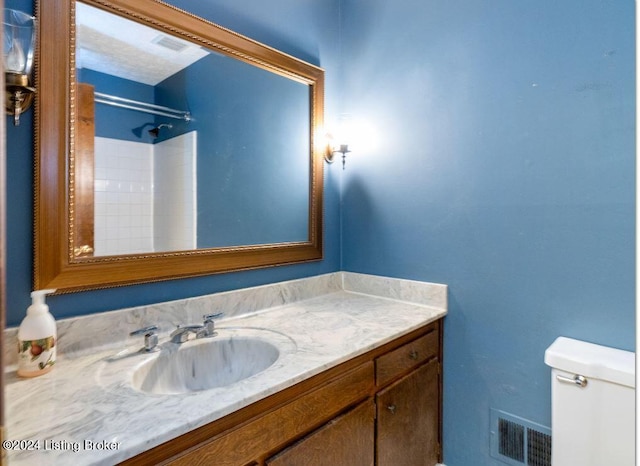 bathroom with vanity, a shower, and toilet