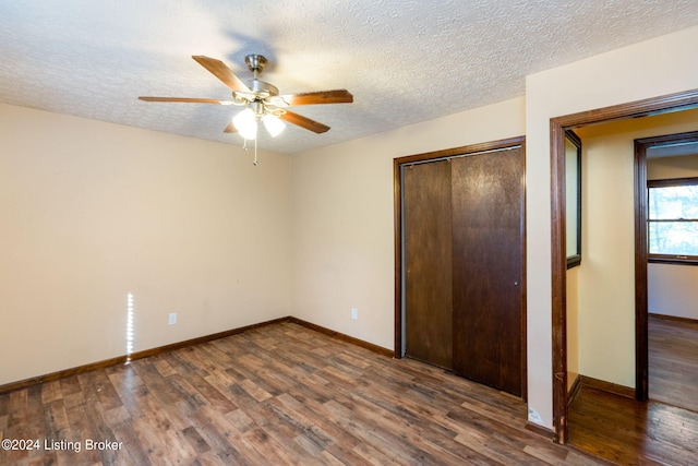 unfurnished bedroom featuring ceiling fan, dark wood-type flooring, a closet, and a textured ceiling