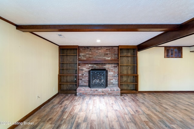 unfurnished living room featuring beamed ceiling, a fireplace, hardwood / wood-style floors, and a textured ceiling