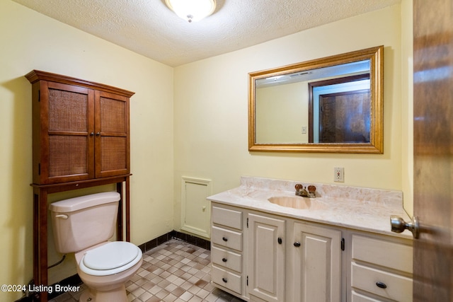 bathroom with vanity, toilet, tile patterned flooring, and a textured ceiling