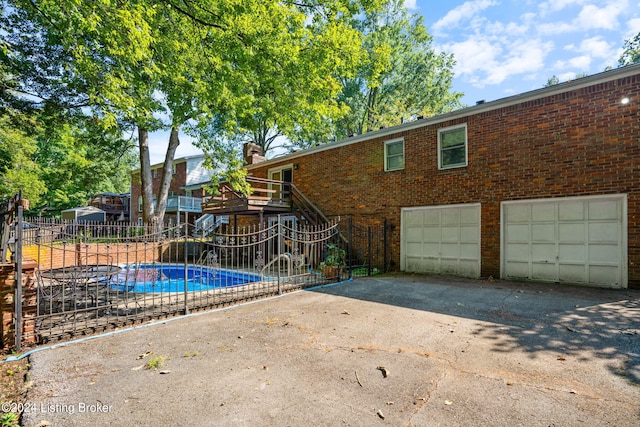 back of property with a garage and a fenced in pool