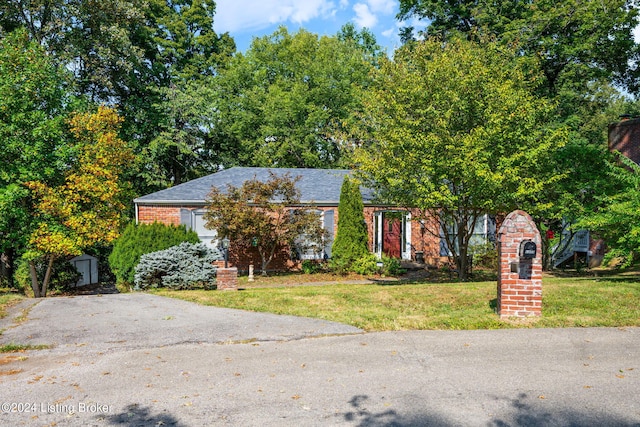 obstructed view of property with a storage shed and a front lawn