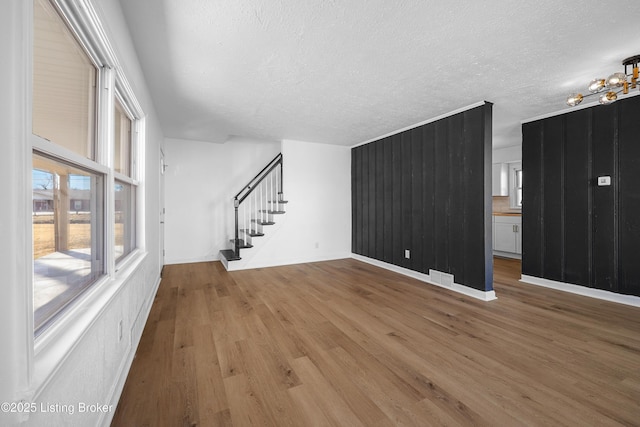 unfurnished living room with wood-type flooring, a chandelier, and a textured ceiling