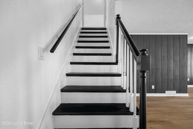 stairway with hardwood / wood-style floors and wood walls