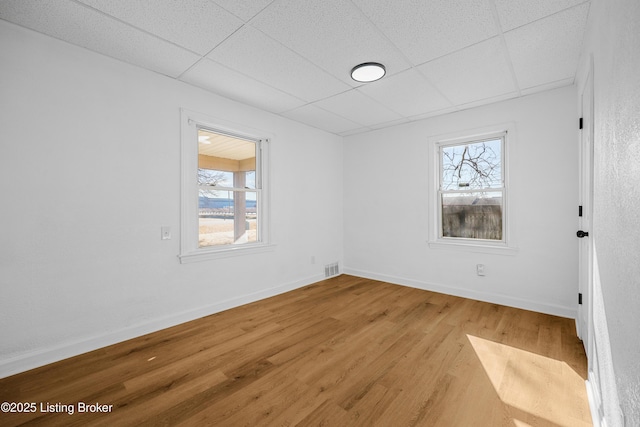 unfurnished room with hardwood / wood-style floors, plenty of natural light, and a paneled ceiling