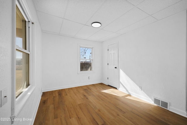 unfurnished room with wood-type flooring and a drop ceiling