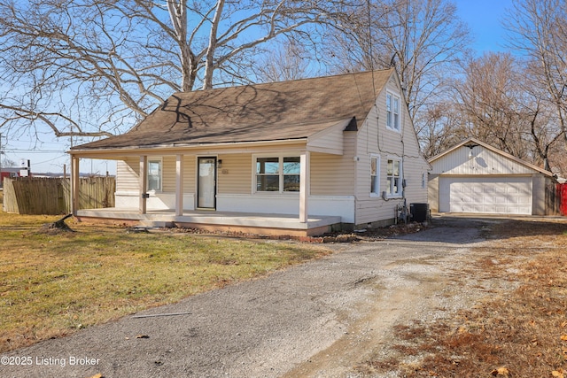 view of front of property featuring central AC unit, a garage, covered porch, an outbuilding, and a front lawn