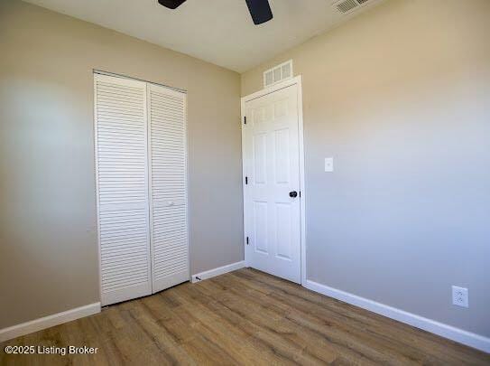 unfurnished bedroom with hardwood / wood-style floors, a closet, and ceiling fan