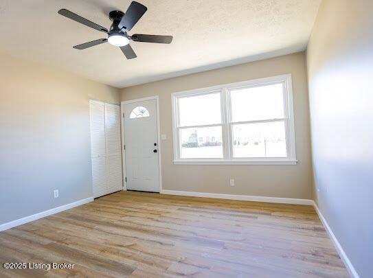 entryway with a textured ceiling, light hardwood / wood-style flooring, and ceiling fan